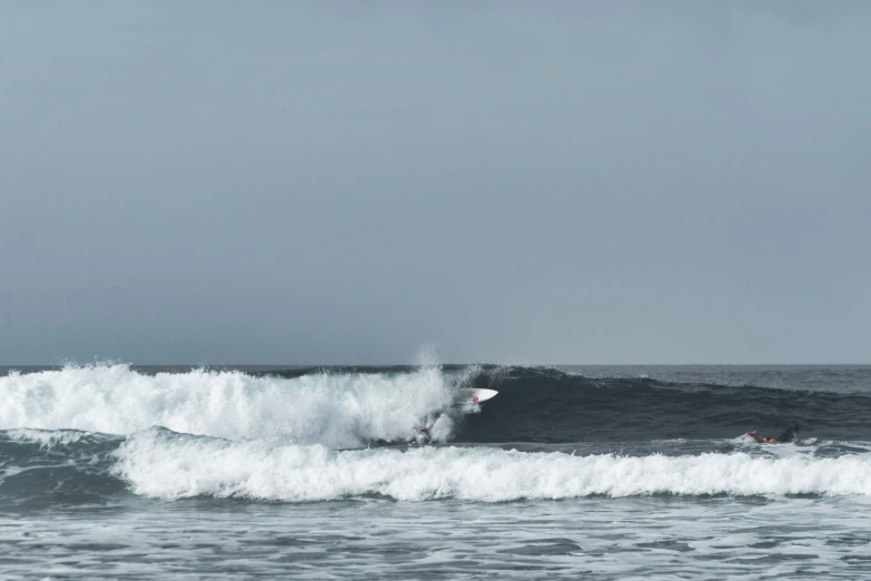 surfer riding breaking wave in ocean while others watch