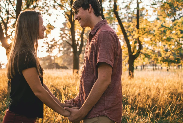 couple standing in tall grass holding hands