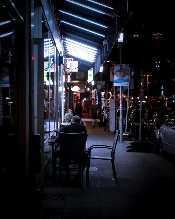 there is a man sitting at a table outside at night