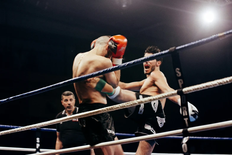 two men boxing in a ring with one wearing a boxing glove