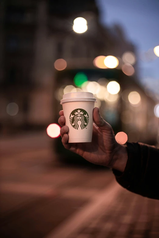 someone holding up a starbucks cup at night