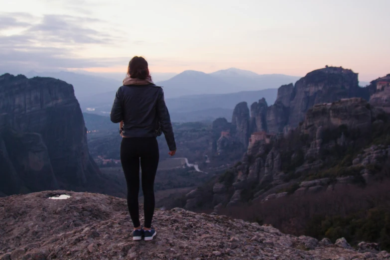 a woman is standing at the edge of a cliff