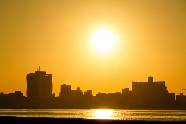 the sun rises over a city skyline as seen from across a body of water