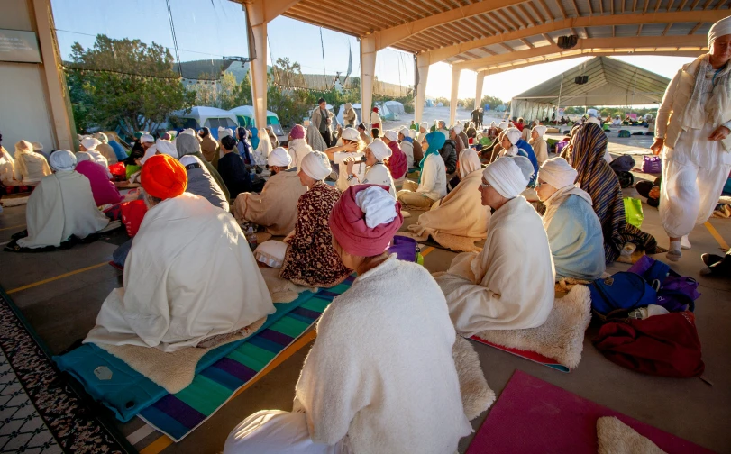 many people in white dresses sitting under a covering