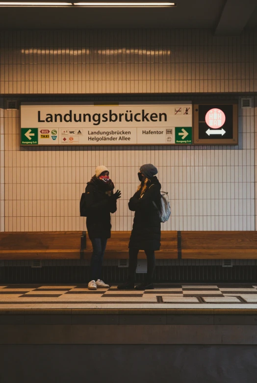 two people stand near a bench at an airport