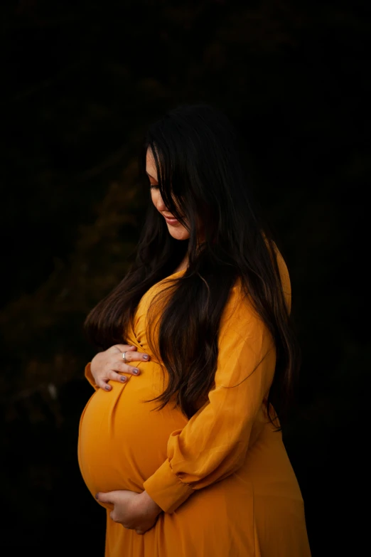 a woman in a yellow sweater is holding her pregnant bump