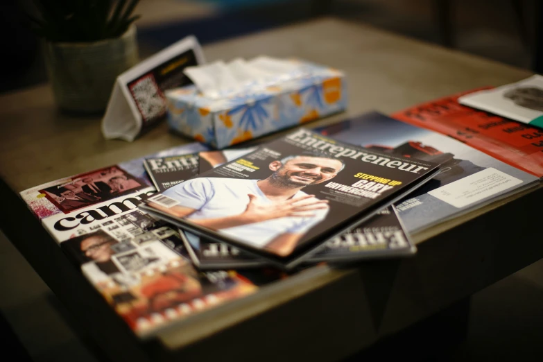 several magazines laying on a table, all with newspapers in front of them