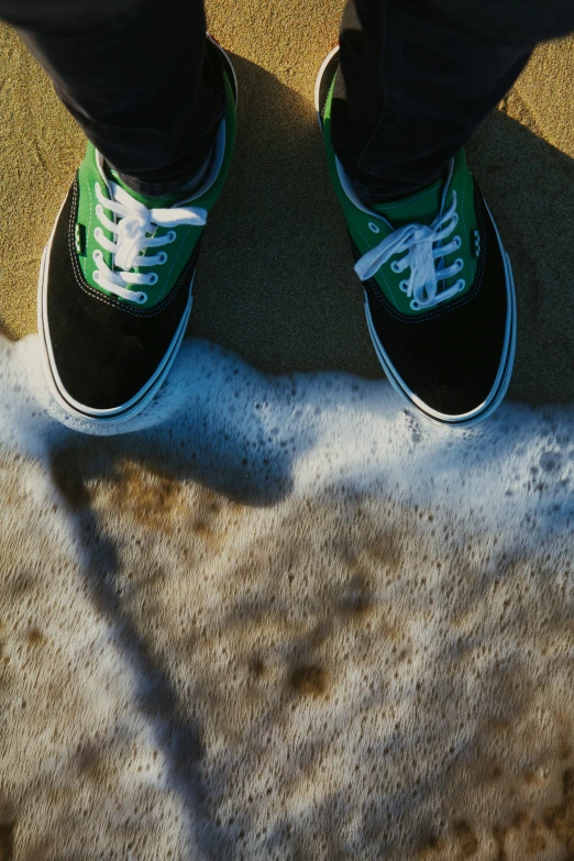 someone wearing green and white sneakers standing on the ground