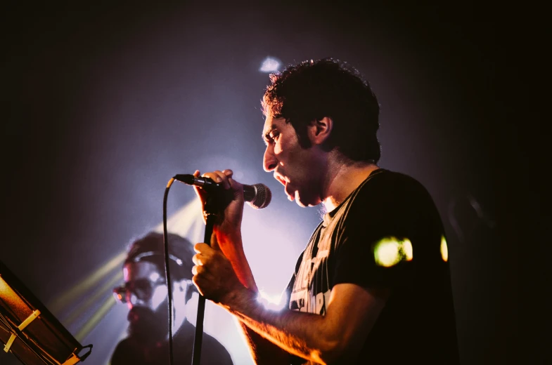 a man on stage with a microphone singing into the microphone