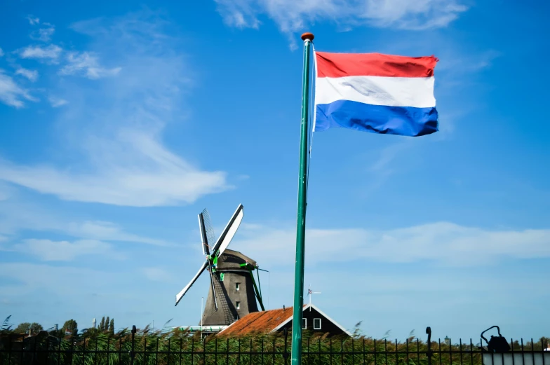 a tall flag pole standing next to a windmill on a field