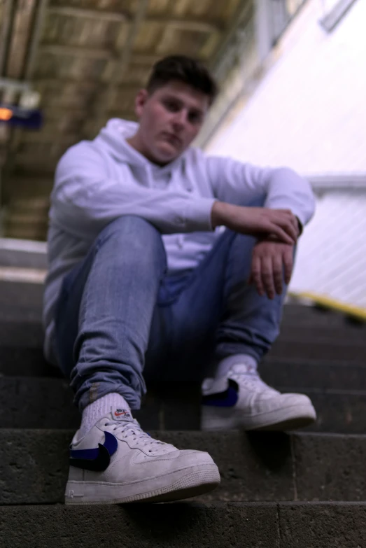 a man sitting on some stairs in a white shirt