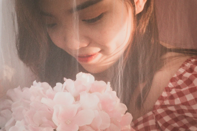 a girl with pink eyes looking down at some flowers