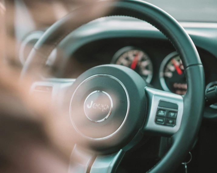 blurry image of a dashboard and steering wheel with hands on the steering wheel