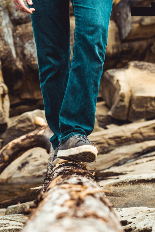 the person is walking on the log in the woods