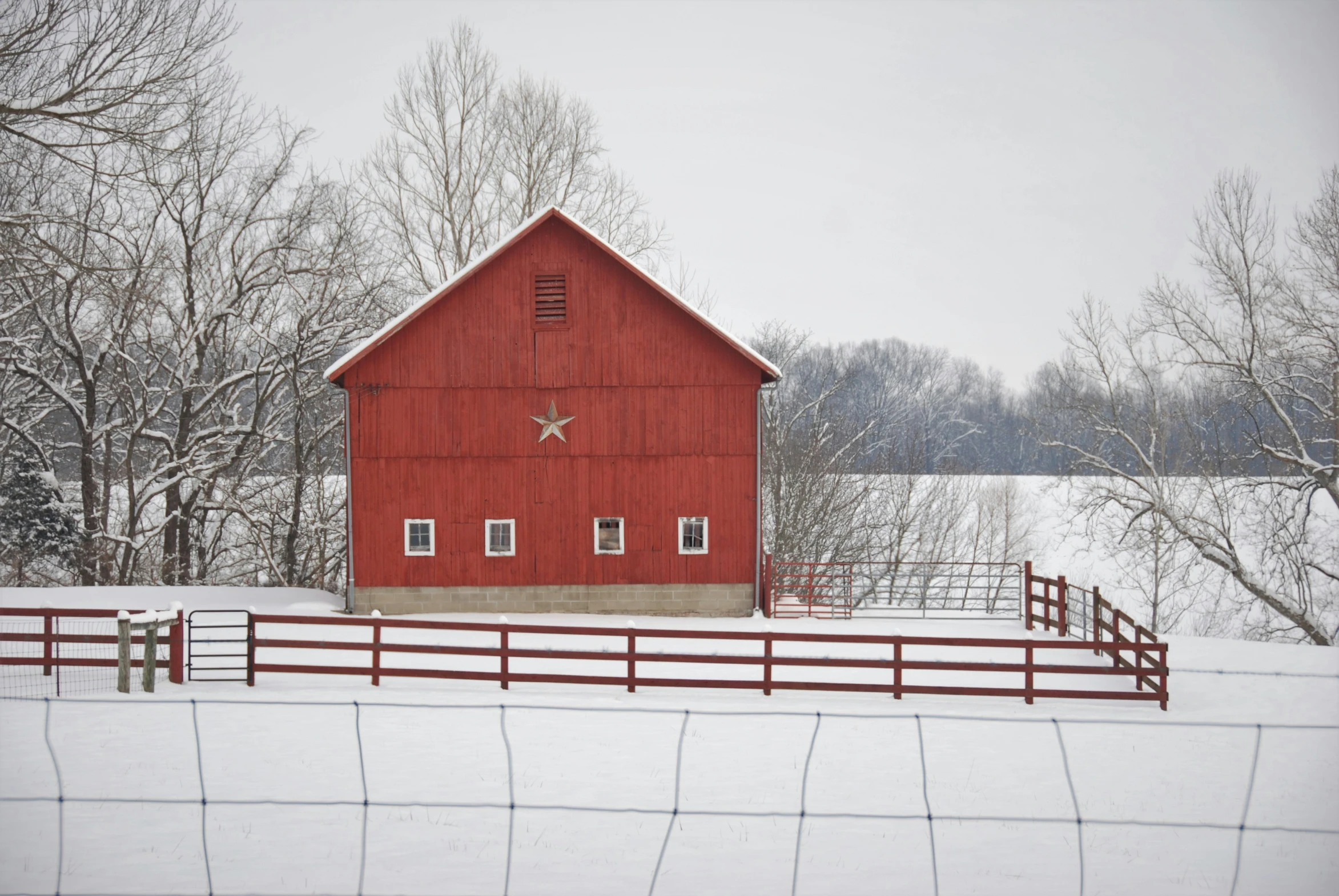 a snow covered field has a farm and a red barn