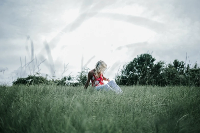 a woman is sitting in a grassy field