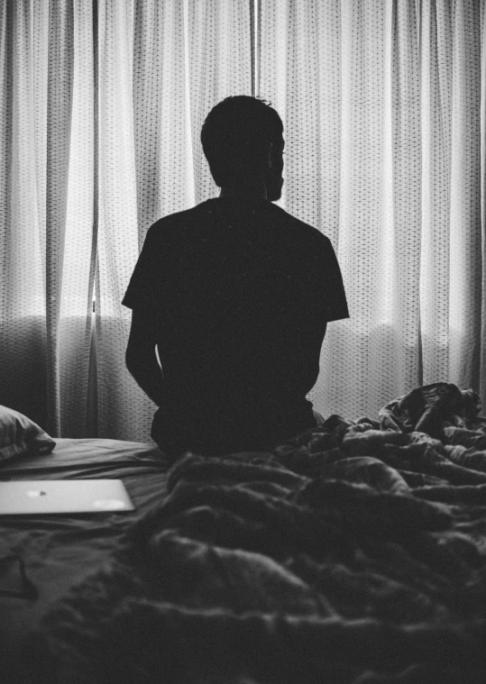 a person sitting in the dark by some curtains