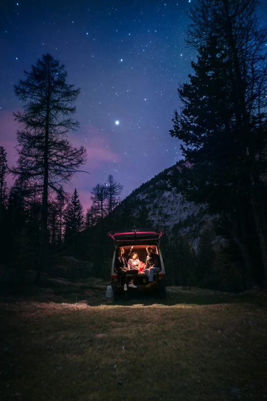 a small cart sitting on a lush green field under a night sky with stars and the moon behind it