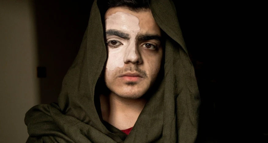 a man wearing a hooded hoodie looks into the camera