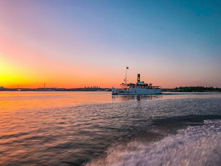 a boat in the water at sunset with a sun setting