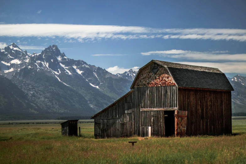 an old barn sitting in the middle of a field