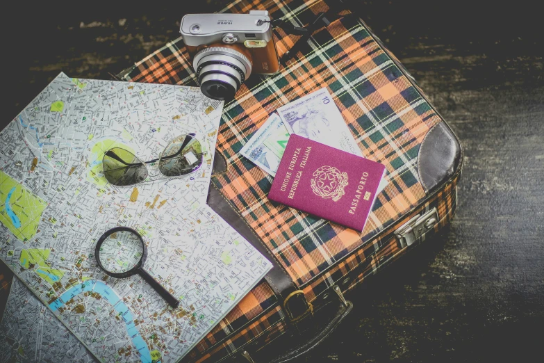 a map and a passport sitting on top of a suitcase