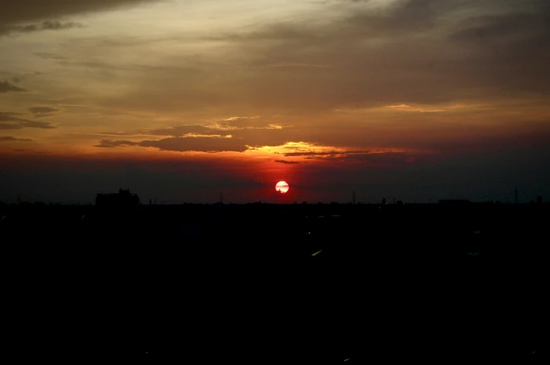 the sun is setting over a city and its dark horizon