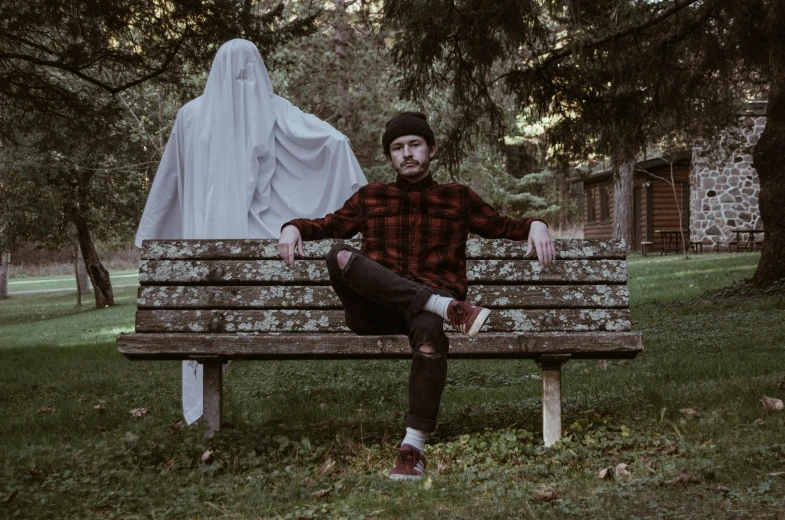 man sitting on bench with statue in background