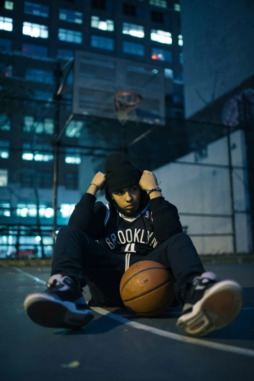a young man sitting on top of a basketball court