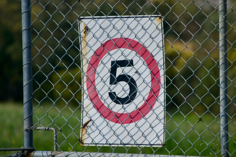 a sign posted on a chain link fence in front of grass