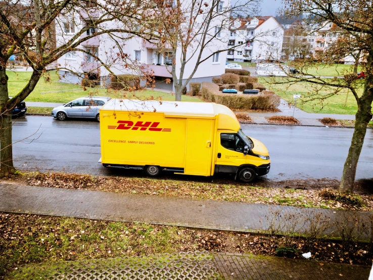 a dhl moving truck is parked near the side of a road