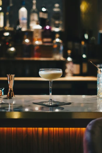 a white martini sitting on top of a counter next to a bartender