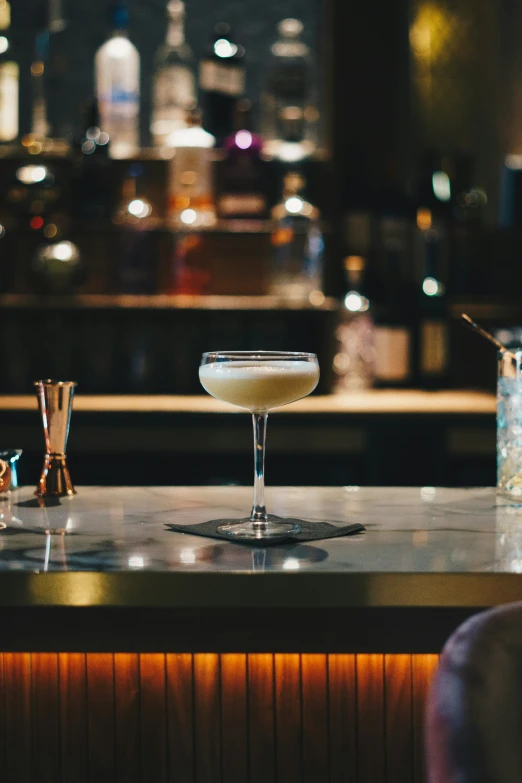 a white martini sitting on top of a counter next to a bartender