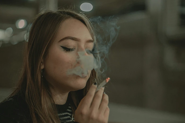 a woman with long hair is smoking a cigarette