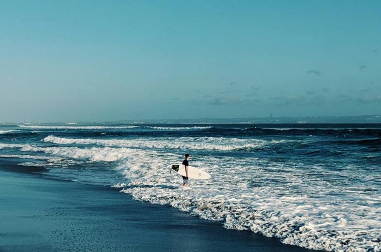 there is a male surfer that is walking into the ocean