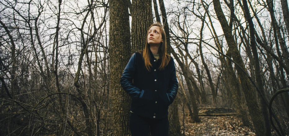 a woman standing in the woods next to a tree