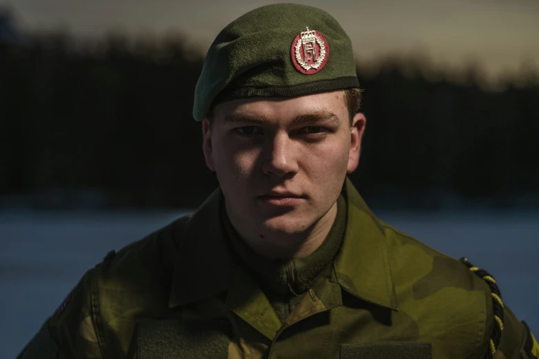 a man in a army uniform is wearing a red cross on the cap