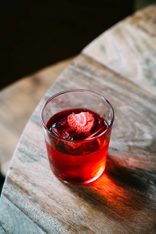 a glass full of liquid sitting on top of a wooden table