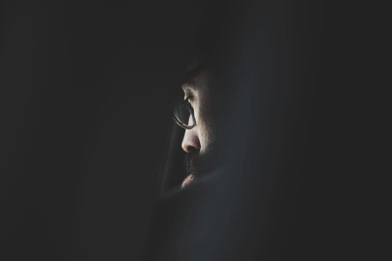 a man staring out of the corner of a dark room