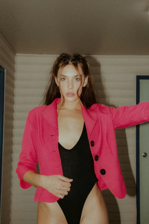 a woman posing in a pink blazer and bathing suit