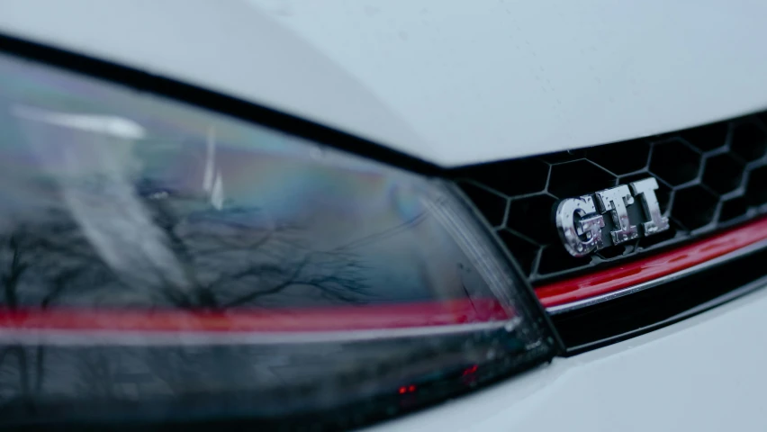 the front lights of a car with trees reflected in it