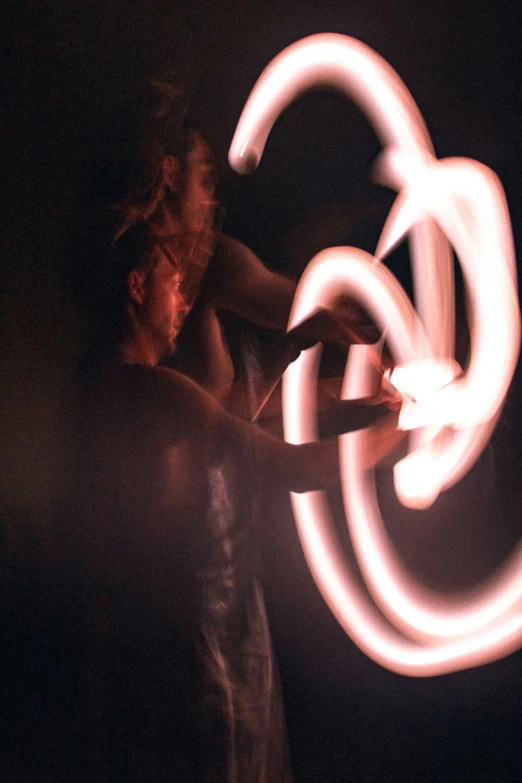 woman spinning light wands at night on her shoulder