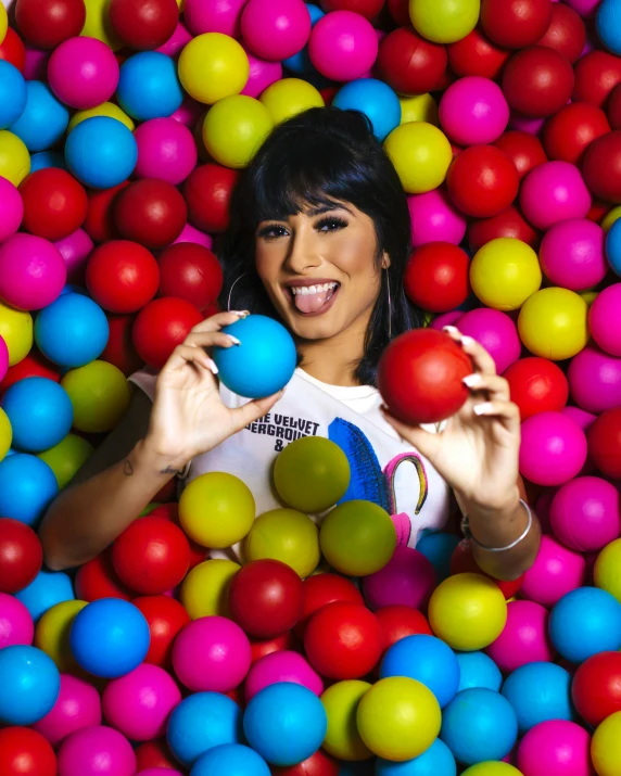 a woman in the midst of ball pit with her hands on balls