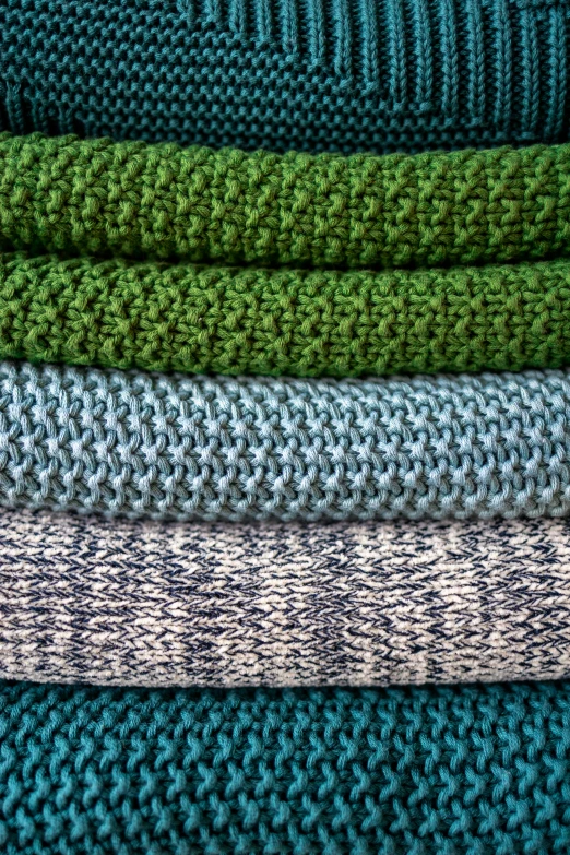 blue and green sweaters stacked up in a row