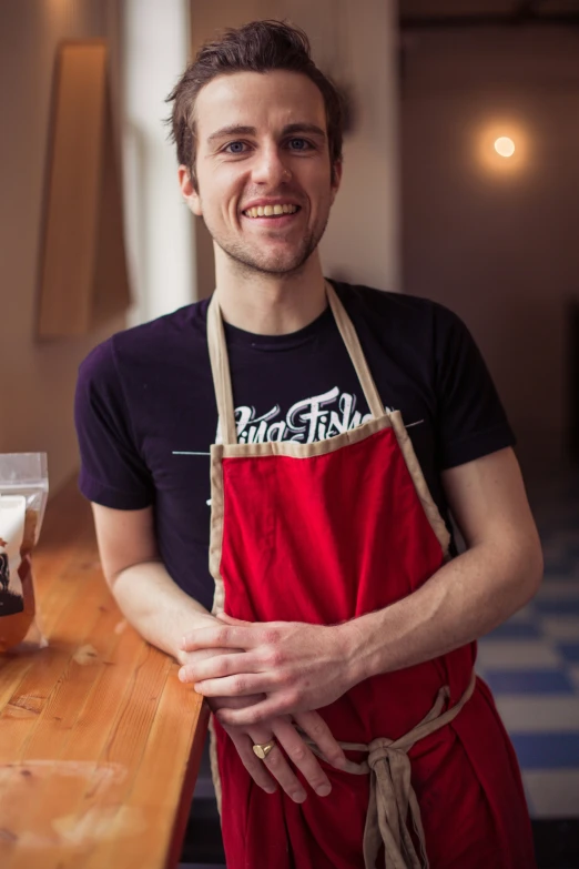 a man smiles as he is holding a jar of honey