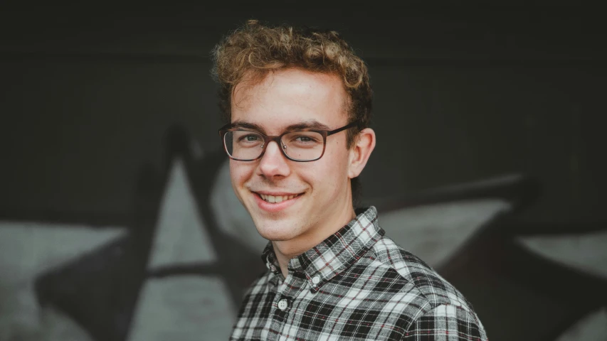 a man with glasses is standing in front of a black background