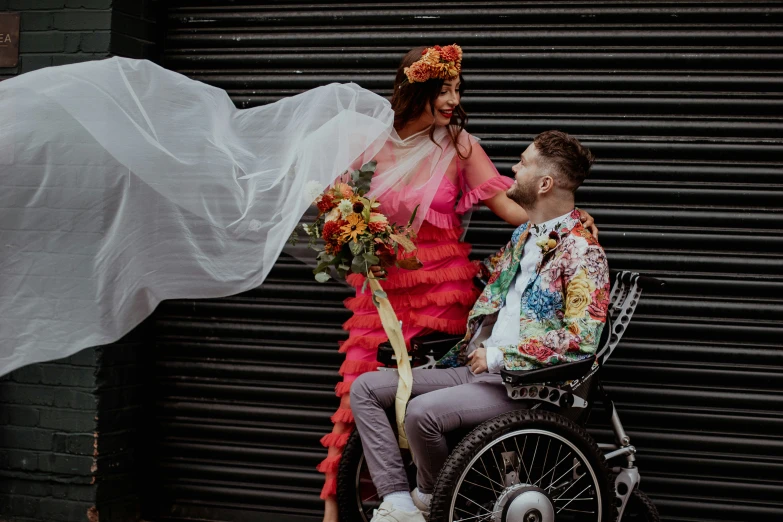 a man standing next to a woman sitting on top of a bike