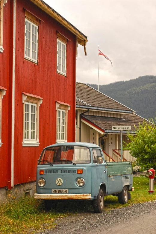 the vintage volkswagen van is parked on a street in front of a red house