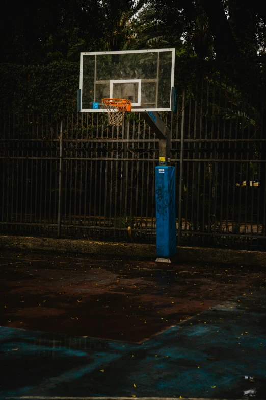 a basketball goal and a blue trashcan are in the street