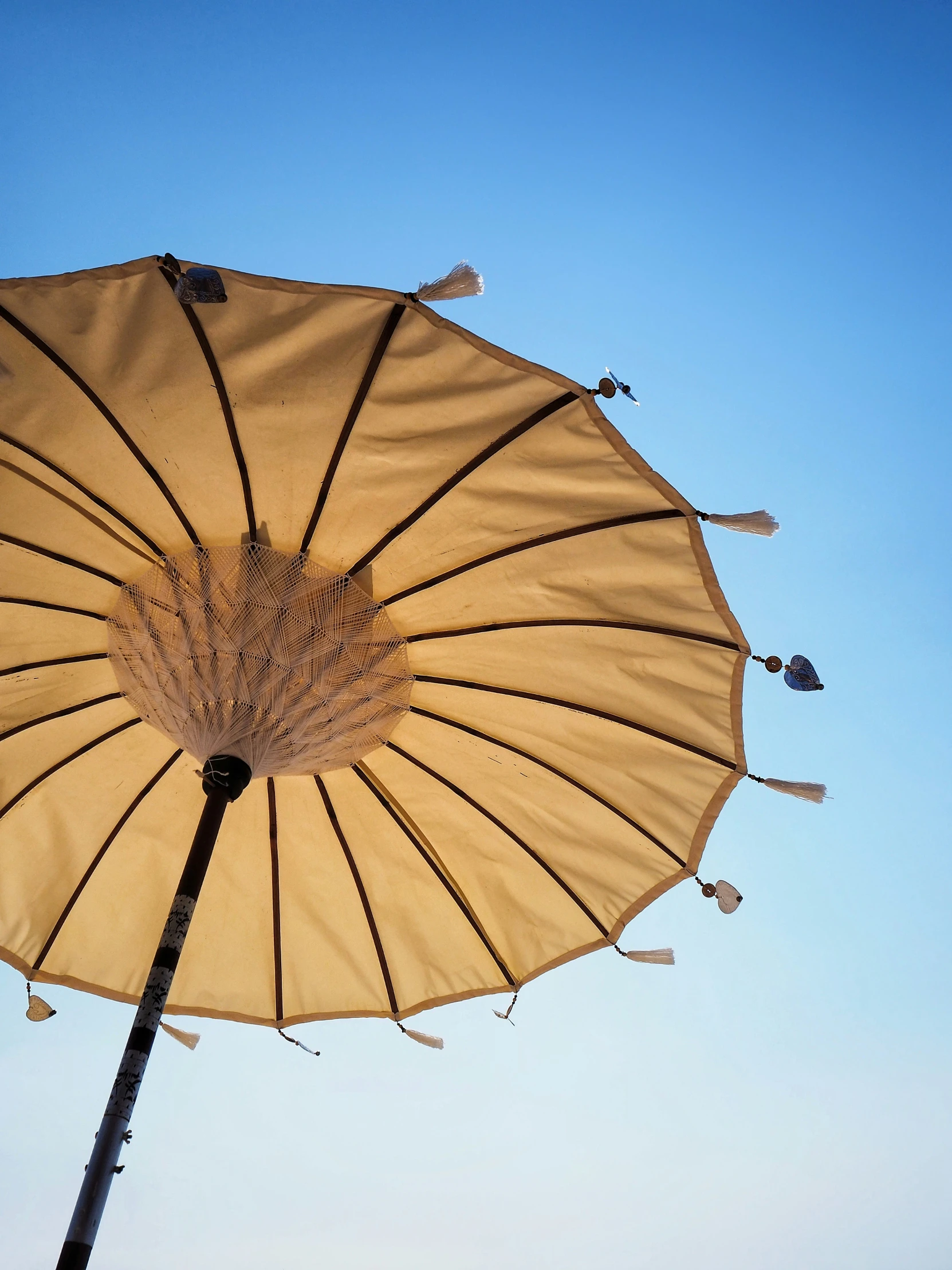 a white umbrella with brown strips hanging from it